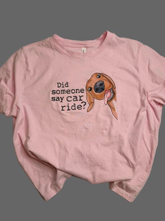 Pink t-shirt with a dog graphic and text on a grey background
