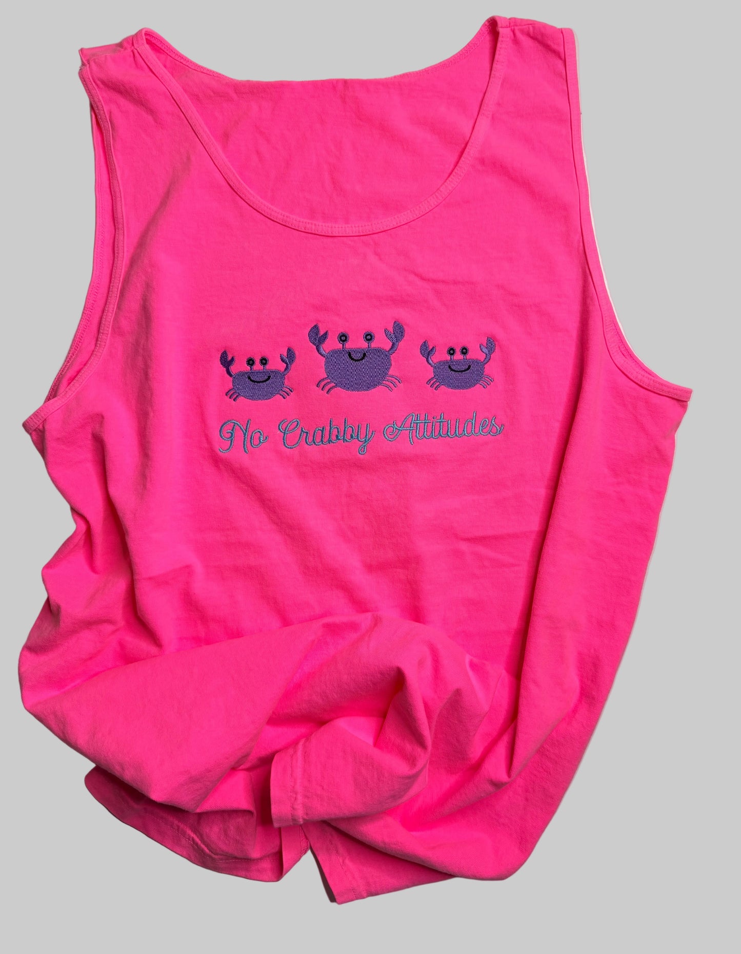 Pink tank top with crab design and text on a gray surface