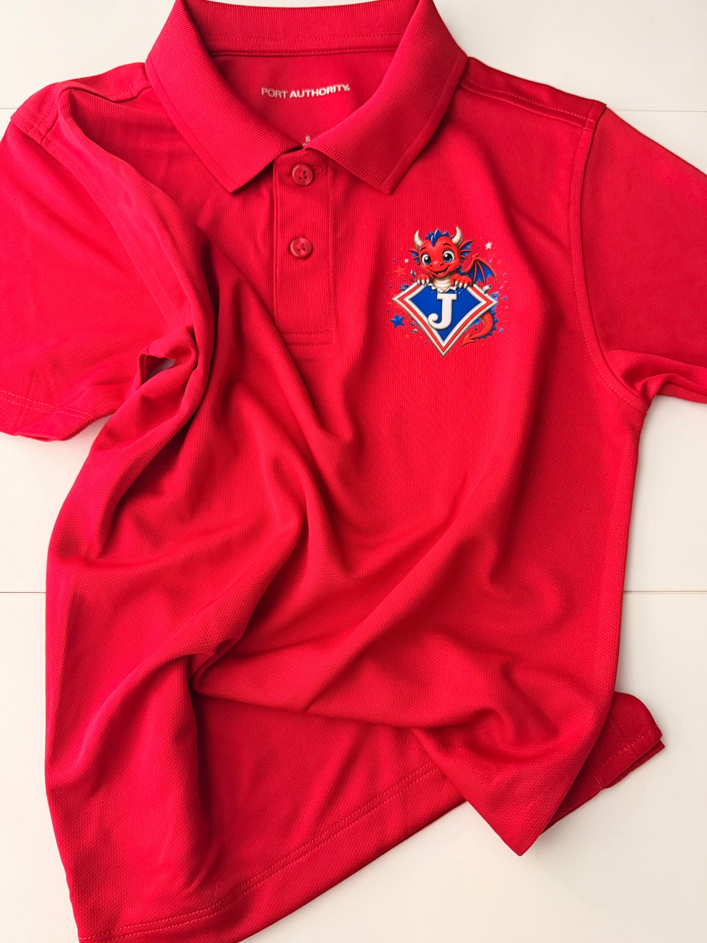 Youth Moisture Wicking Polo with DTF print of cute Dragon Bursting from Logo