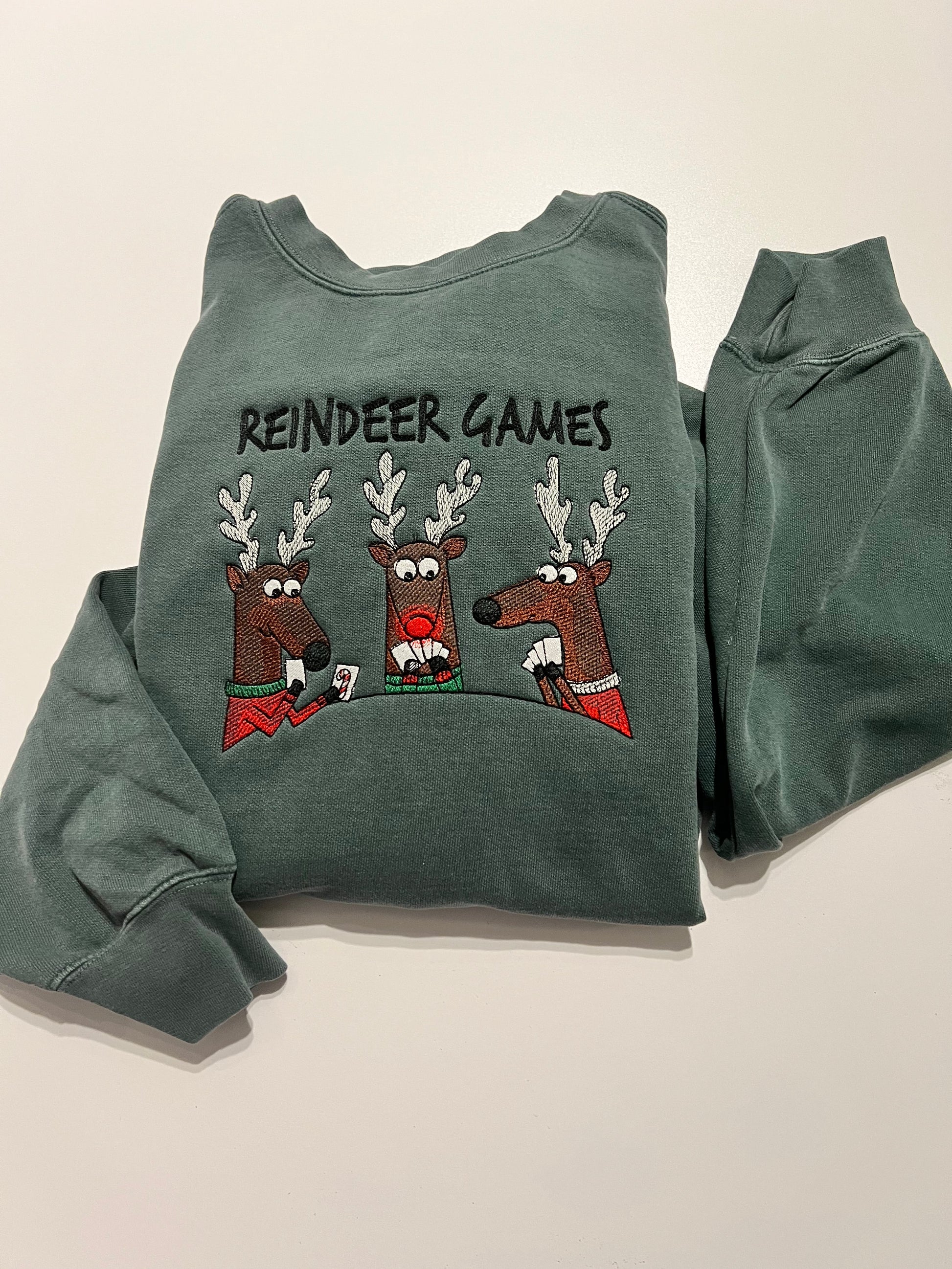 Green sweatshirt with reindeer graphics and 'Reindeer Games' text on a beige background