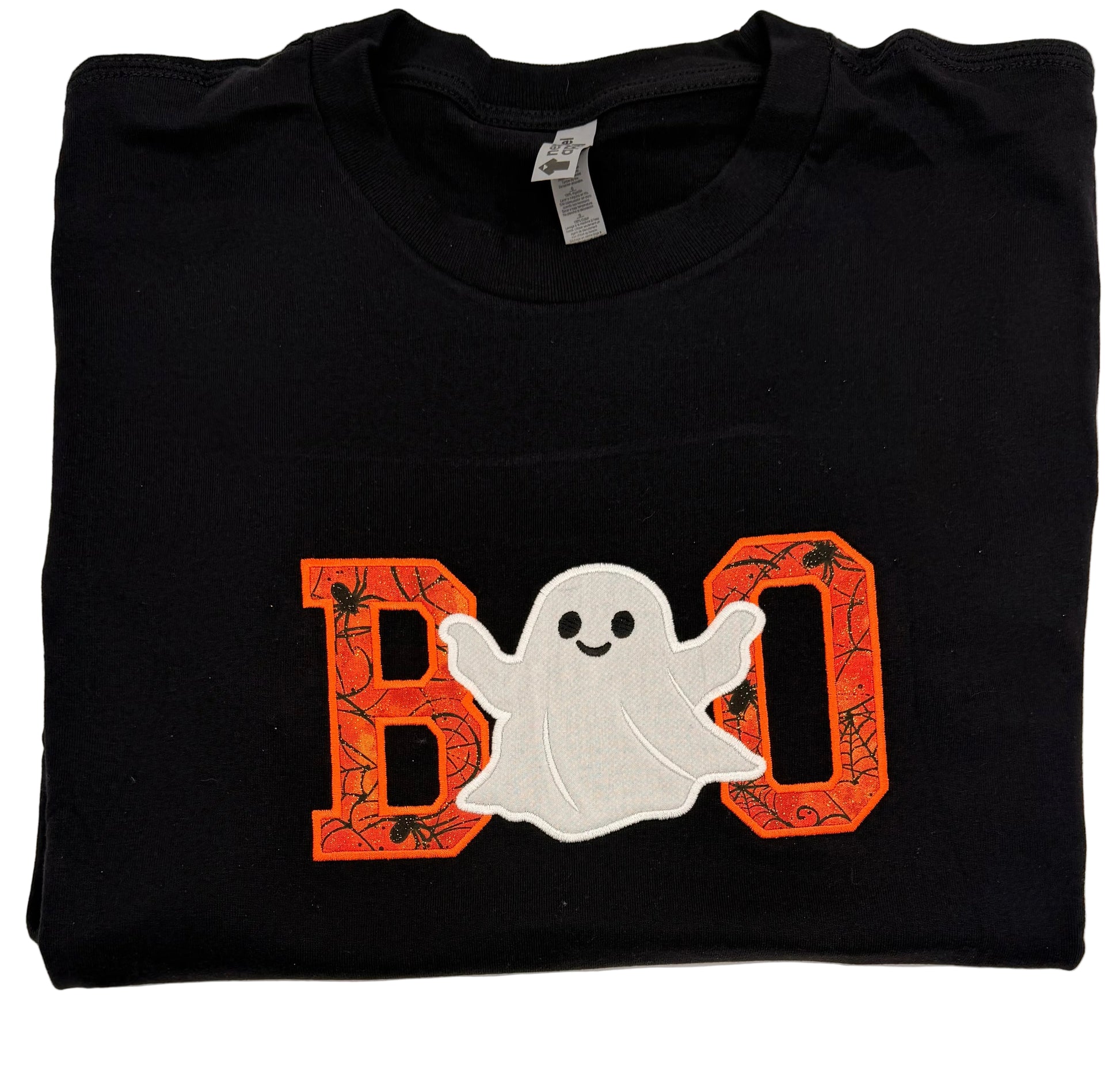 A folded black t-shirt featuring a 'BOO' graphic with orange spiderweb-patterned letters and a white ghost in the middle, displayed on a white background.