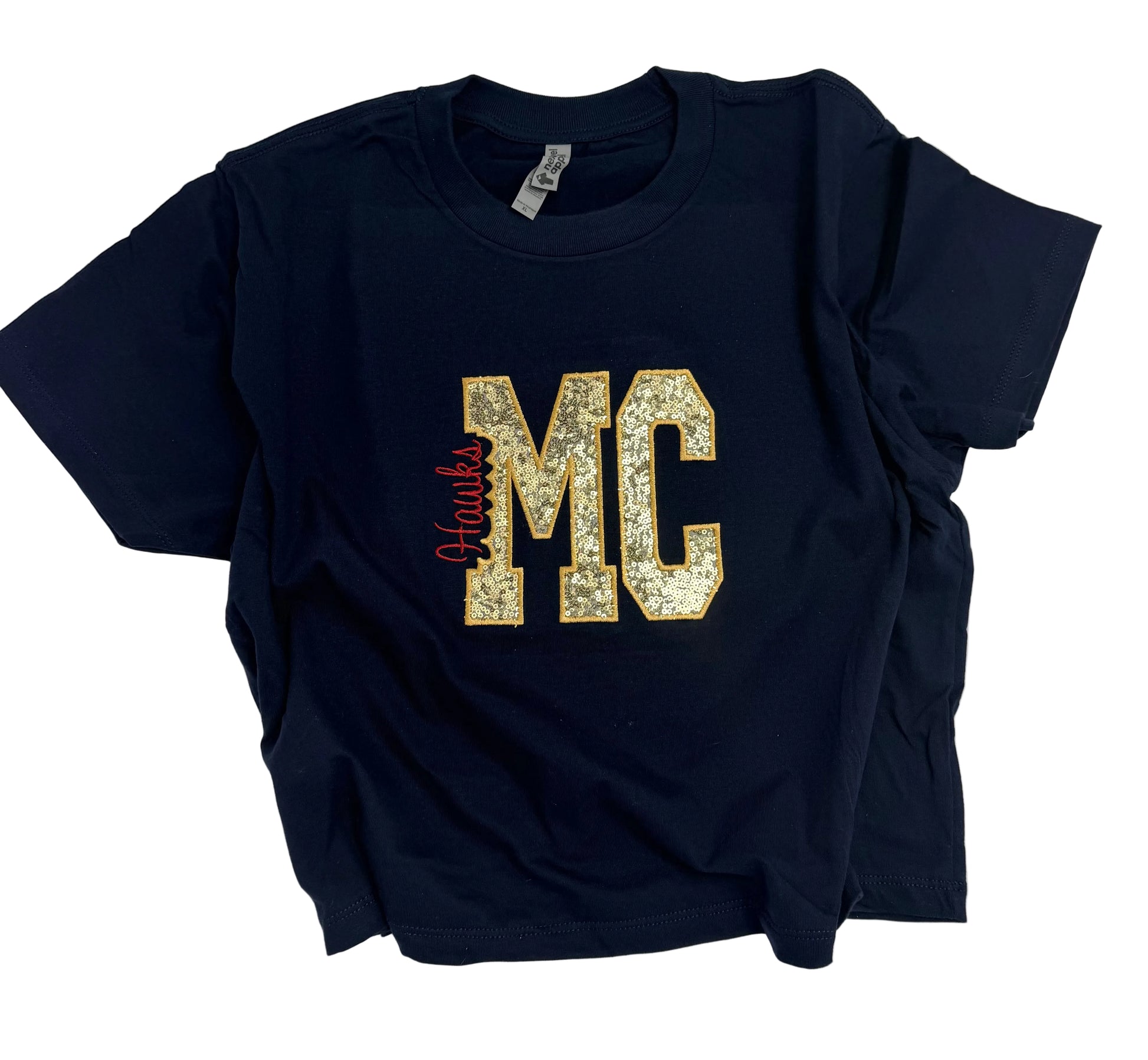 A navy blue short-sleeve t-shirt with a glittery gold 'MC' graphic and a red script 'Hawks' detail on the front, laid flat on a white background.