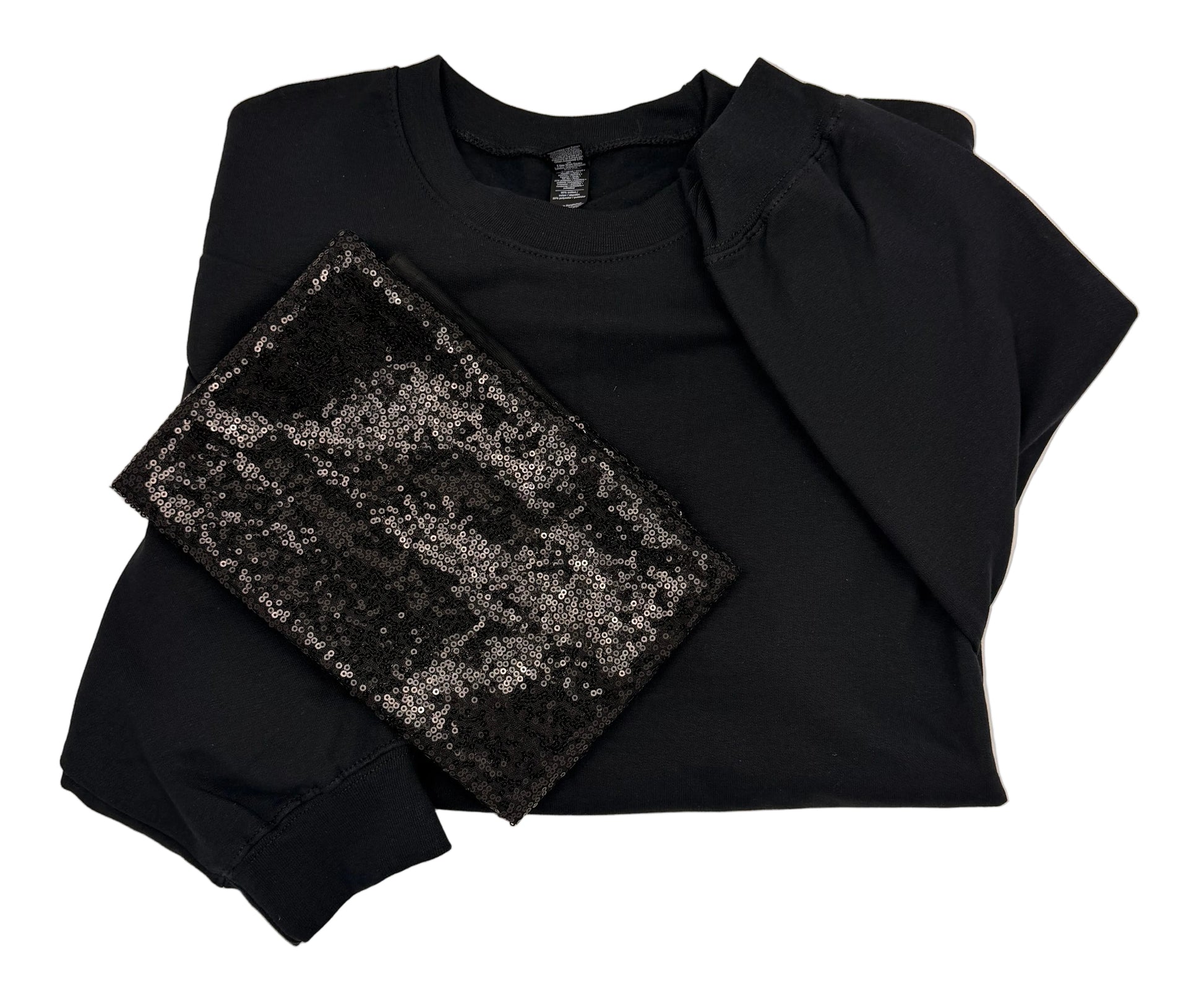 A black long-sleeve crewneck sweatshirt with dramatic puff sleeves, laid flat on a white surface alongside a black sequin material.